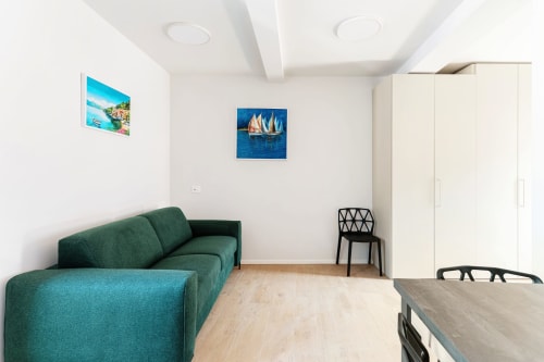 Camera moderna del Lago Suites Como con divano verde, pavimenti in legno, arte costiera e vista sulla città