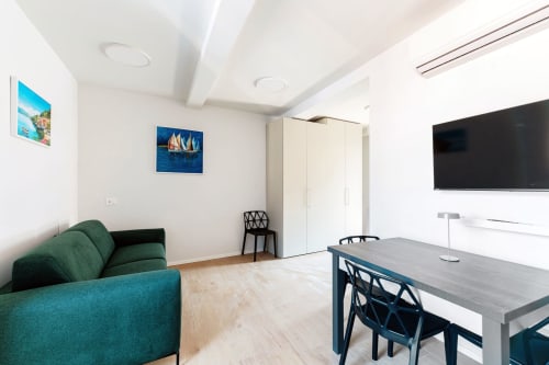 Camera moderna del Lago Suites Como con divano turchese, TV a schermo piatto, scrivania e opere d'arte nautiche