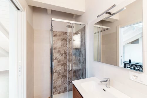 Bagno moderno di Lago Suites Como con cabina doccia in vetro, mobile bianco, specchio e illuminazione LED