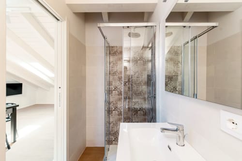 Bagno moderno presso Lago Suites Como con doccia in vetro, vanità bianca e parete rivestita in piastrelle decorative