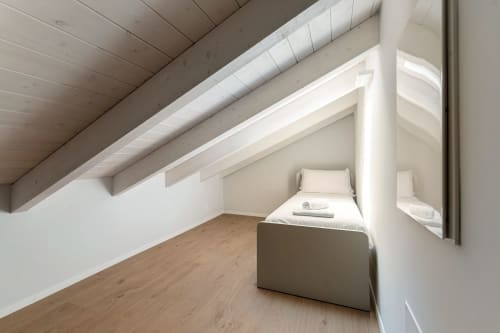 Accogliente camera da letto in mansarda presso Lago Suites Como con letto singolo, pavimento in legno e soffitto inclinato bianco con luce naturale