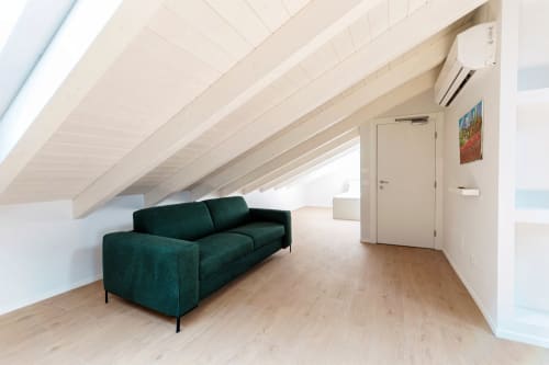 Camera da letto in mansarda moderna di Lago Suites Como con divano verde scuro, pavimenti in legno e travi a vista