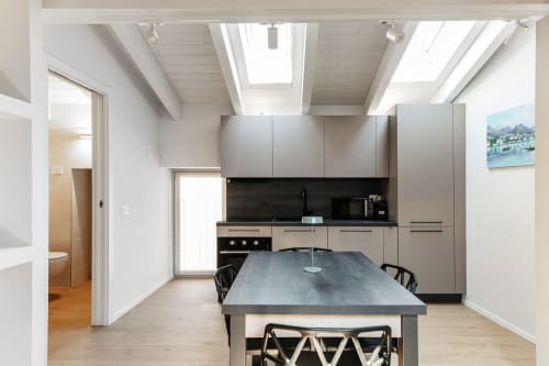 Cucina e zona pranzo moderna presso Lago Suites Como con lucernario, banconi neri e vista sulla città