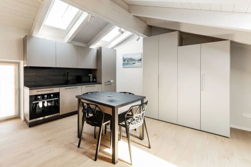 Cucina moderna in loft presso Lago Suites Como con lucernario, elettrodomestici neri, tavolo da pranzo e arte con vista città