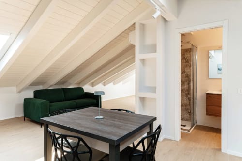 Suite attica moderna a Lago Suites Como con divano verde, tavolo da pranzo e bagno en-suite