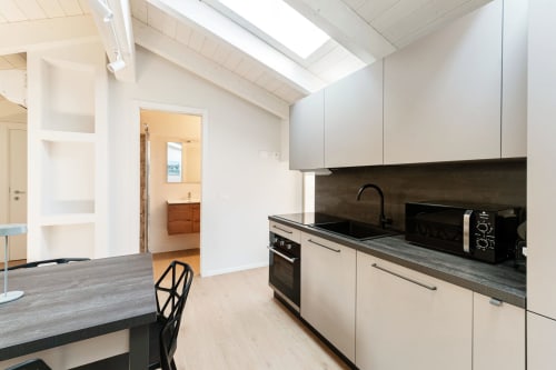 Cucina moderna della Suite Lago 401 a Como con mobili bianchi, piani scuri e lucernario