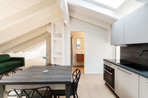 Moderna camera in stile loft a Lago Suites Como con cucina, zona pranzo, divano verde e lucernario