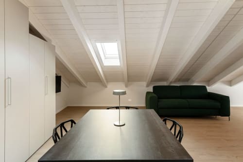 Suite moderna in mansarda presso Lago Suites Como con lucernario, tavolo da pranzo, divano nero e design minimalista