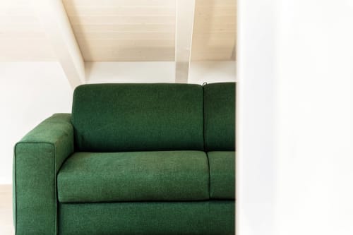 Poltrona imbottita verde nella moderna camera dell'hotel Como con soffitto bianco e dettagli architettonici presso Lago Suites
