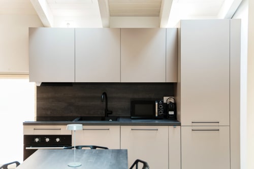 Angolo cucina moderno nella Suite Lago Como 401 con mobili bianchi, backsplash scuro e elettrodomestici in acciaio inox