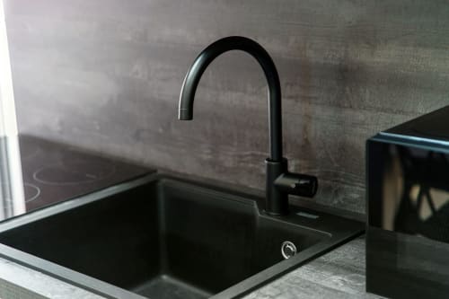 Lavello e rubinetto cucina neri moderni nella suite 401 dell'hotel Lago Suites Como con vista città