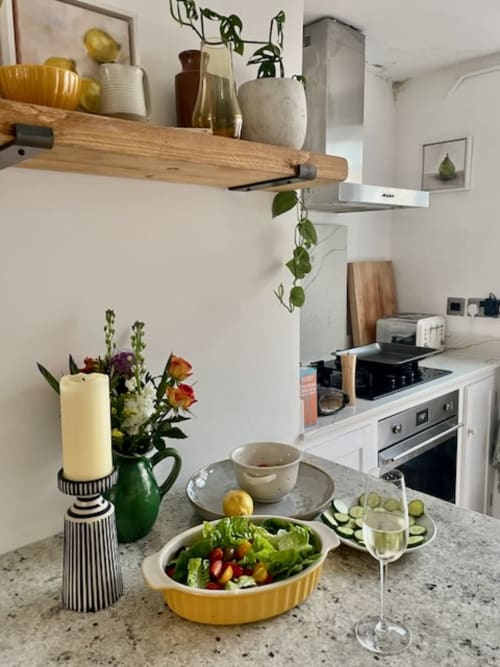 Modern kitchen at 2 Doves Holiday Property in Exeter with dining table, fresh salad, wine glasses, and potted flowers
