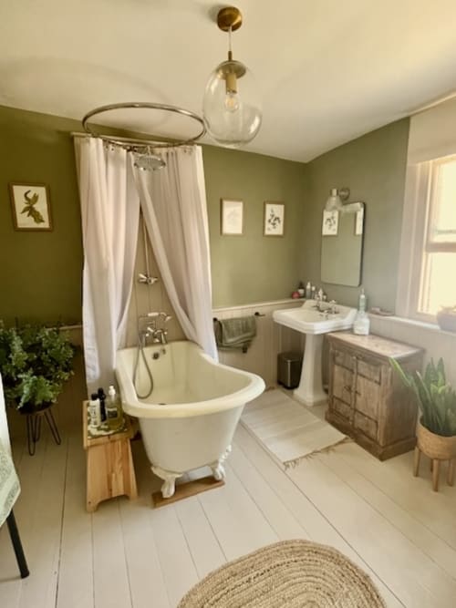 Elegant bathroom at 2 Doves Holiday Property in Exeter featuring freestanding bathtub, pedestal sink, and sage green walls