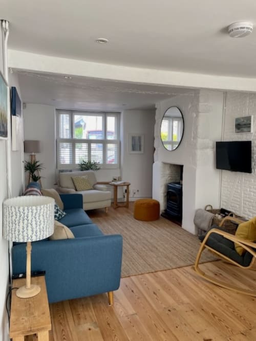 Modern villa living room at 2 Doves Holiday Property in Exeter with blue armchair, cream sofa, fireplace, and TV