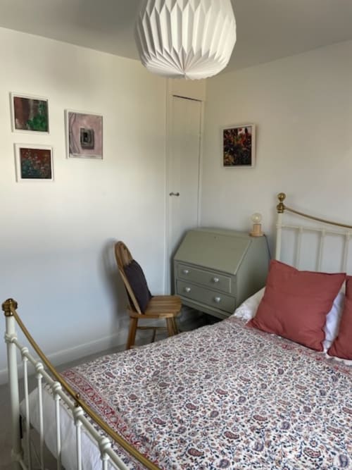 Cozy bedroom at 2 Doves Holiday Property in Topsham with white iron bed, green chest of drawers, and framed artwork