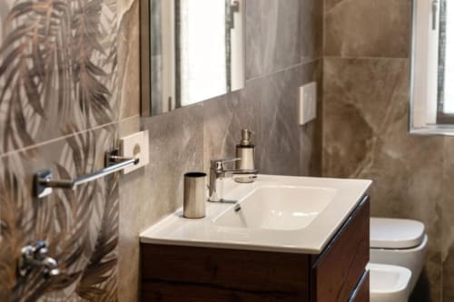 Bagno moderno di Lago Suites Como con lavabo bianco, rubinetteria cromata e pareti piastrellate