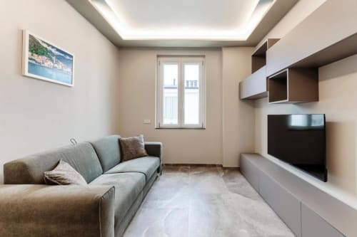 Elegante soggiorno moderno presso Lago Suites Como con divano, TV a schermo piatto, scaffalature a parete e vista sulla città