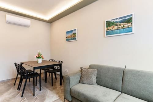 Appartamento moderno presso Lago Suites Como con tavolo da pranzo, divano e opere d'arte con vedute del lago sulle pareti