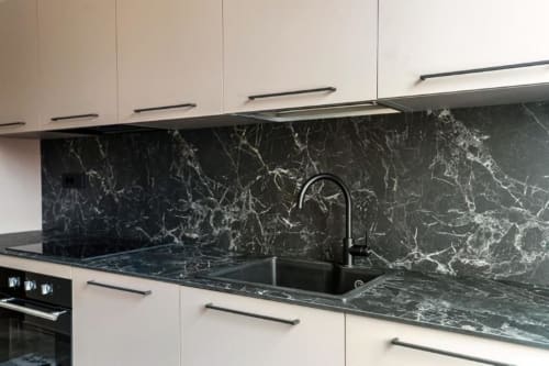 Cucina moderna in appartamento Lago Suites Como con mobili bianchi, top e backsplash in marmo nero, acciaio inox