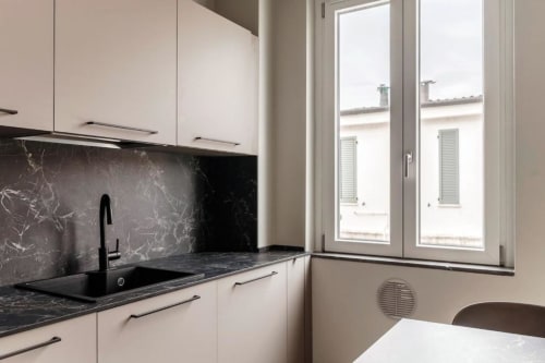 Cucina moderna nell'appartamento Lago Suites Como con i mobili bianchi, piano di lavoro e rivestimento in marmo nero, lavello nero e
