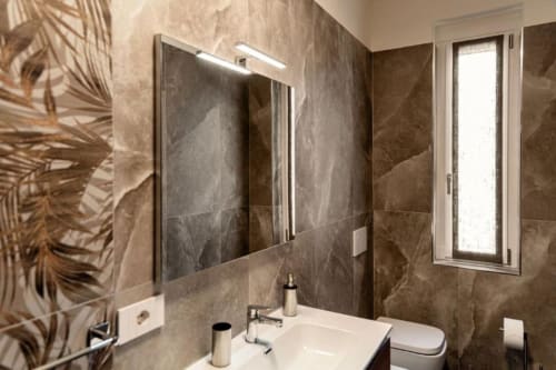 Bagno moderno presso Lago Suites Como con rivestimento in piastrelle marrone, specchio illuminato, lavabo bianco e finiture contemporanee