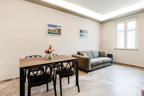 Moderno soggiorno nella suite di Lago Como con tavolo da pranzo, divano e ampie finestre con vista sul lago