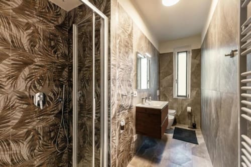 Bagno moderno a Lago Suites Como con piastrelle tropicali, vanity scuro e doccia effetto pioggia