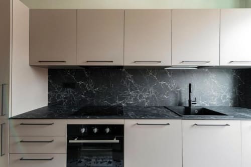 Cucina moderna presso Lago Suites Como con mobili bianchi, backsplash e piano in marmo nero, forno incassato e