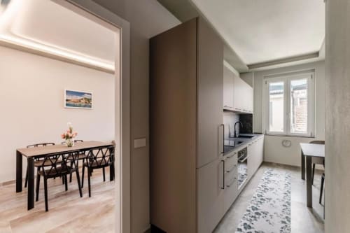Cucina e zona pranzo moderne con arredamento bianco, piani neri e vista sulla città - Lago Suites, Como