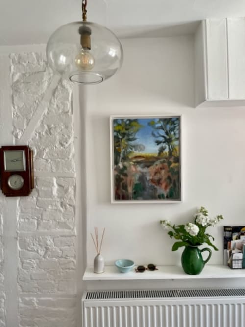 Modern white brick wall with globe pendant light, landscape painting, green vase with white flowers, and retro clock in