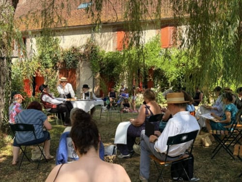 Outdoor garden gathering at Domaine de l'Ocrerie guesthouse in Pourrain with guests seated under willow trees