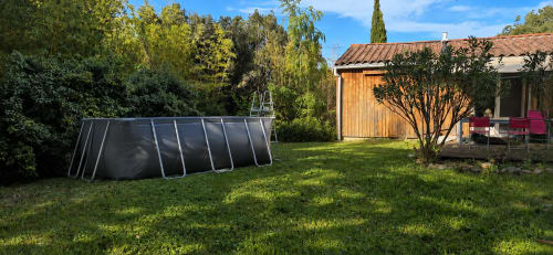 Jardín trasero del refugio Domaine en Terre Happy con piscina rectangular, cabaña de madera y zona de descanso entre árboles frondosos