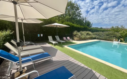 Luxury pool area at Gîte La Vieille Ferme de La Doinie in Saint-Geniès with loungers, umbrellas, and garden views