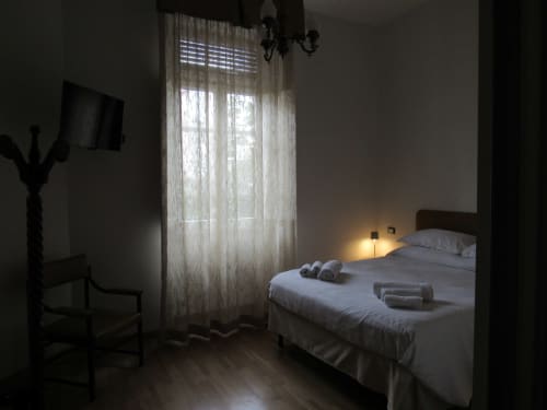 Camera da letto dell'Il 900 B&B di Avezzano con letto bianco, tende trasparenti, pavimento in legno e illuminazione d'ambiente