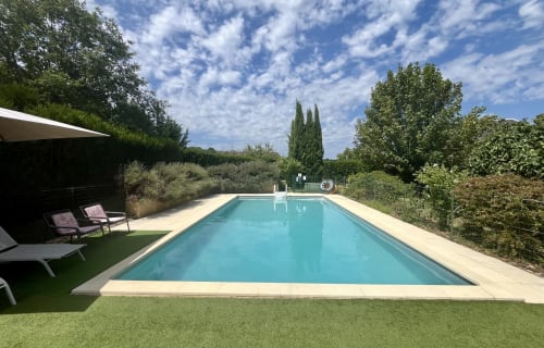 Piscina rectangular con agua turquesa rodeada de césped verde y paisajismo mediterráneo en Gîte La Vieille