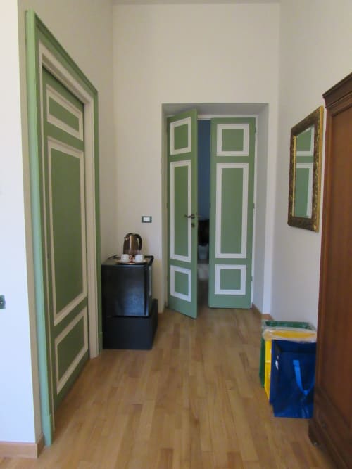 Corridoio della camera Pane presso l'Il 900 B&B di Avezzano, con porte verdi dai bordi bianchi e pavimento in legno