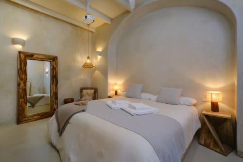 Elegant bedroom with arched alcove, round bed, wooden mirror, warm lighting at EntreArcos Casa Eco-Boutique hotel in Vejer de