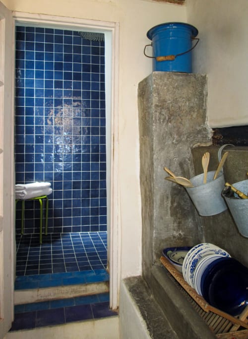 Bagno con piastrelle blu presso il Clos Bb con scaffali contenenti stoviglie e articoli per la casa a Saint-Cyr-sur-Mer