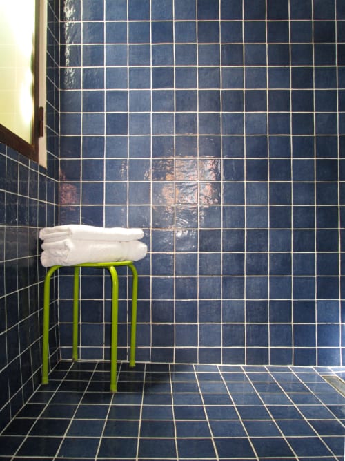 Bagno con piastrelle blu navy alle pareti, porta-asciugamani verde lime con asciugamani bianchi al Clos B&B di Saint-Cyr sur Mer