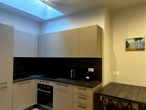 Cucina moderna presso Lago Suites Como con mobili color panna, piano di lavoro nero, forno incasso e lucernario