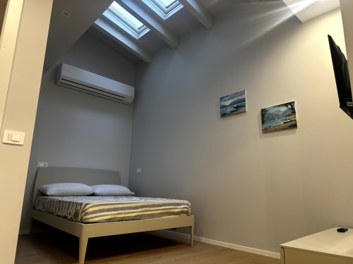 Camera moderna di Lago Suites Como con letto, lucernari, climatizzazione e suggestivi dipinti paesaggistici alle pareti