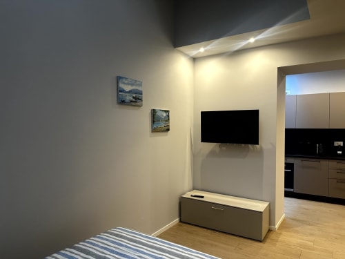 Camera moderna di Lago Suites Como con TV a parete, mobili in legno e tappeto a righe
