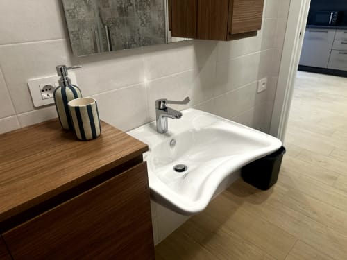 Bagno moderno presso Lago Suites Como con lavabo bianco curvo, mobile in legno, rubinetto cromato e pareti in piastrelle beige
