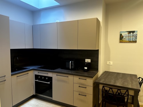 Cucina moderna di Lago Suites Como con mobili color crema, piano in nero, forno incassato e tavolo da pranzo