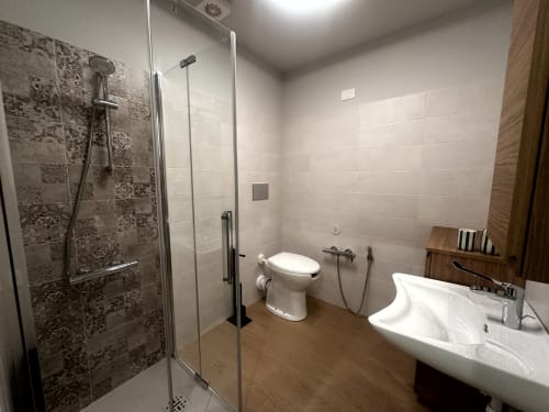 Bagno moderno accessibile a Lago Suites Como con doccia a filo pavimento, WC e lavabo bianco