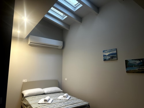 Camera moderna presso Lago Suites Como con finestre a lucernario, aria condizionata, biancheria a righe e opere d'arte paesaggistica alle pareti