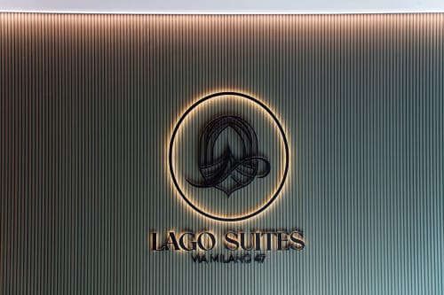 Logo dell'hotel Lago Suites Como con icona elegante di baffi su sfondo di metallo ondulato
