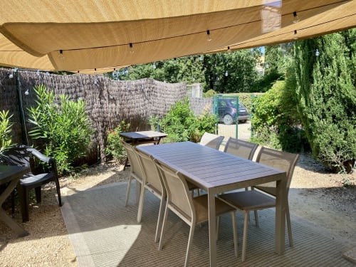 Private garden patio at Le Mas de la Soie cottage with dining table, shade sail, and lush greenery in Entrechaux, France