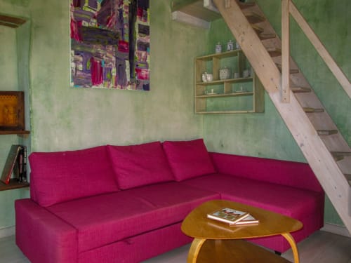 Divano angolare rosa vivace nel salotto verde menta del Clos Bb, Saint-Cyr sur Mer, con tavolo in legno e scala