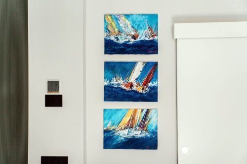 Tre vivaci dipinti di barche a vela esposti presso Lago Suites Como, raffiguranti yacht colorati che corrono su acque azzurre